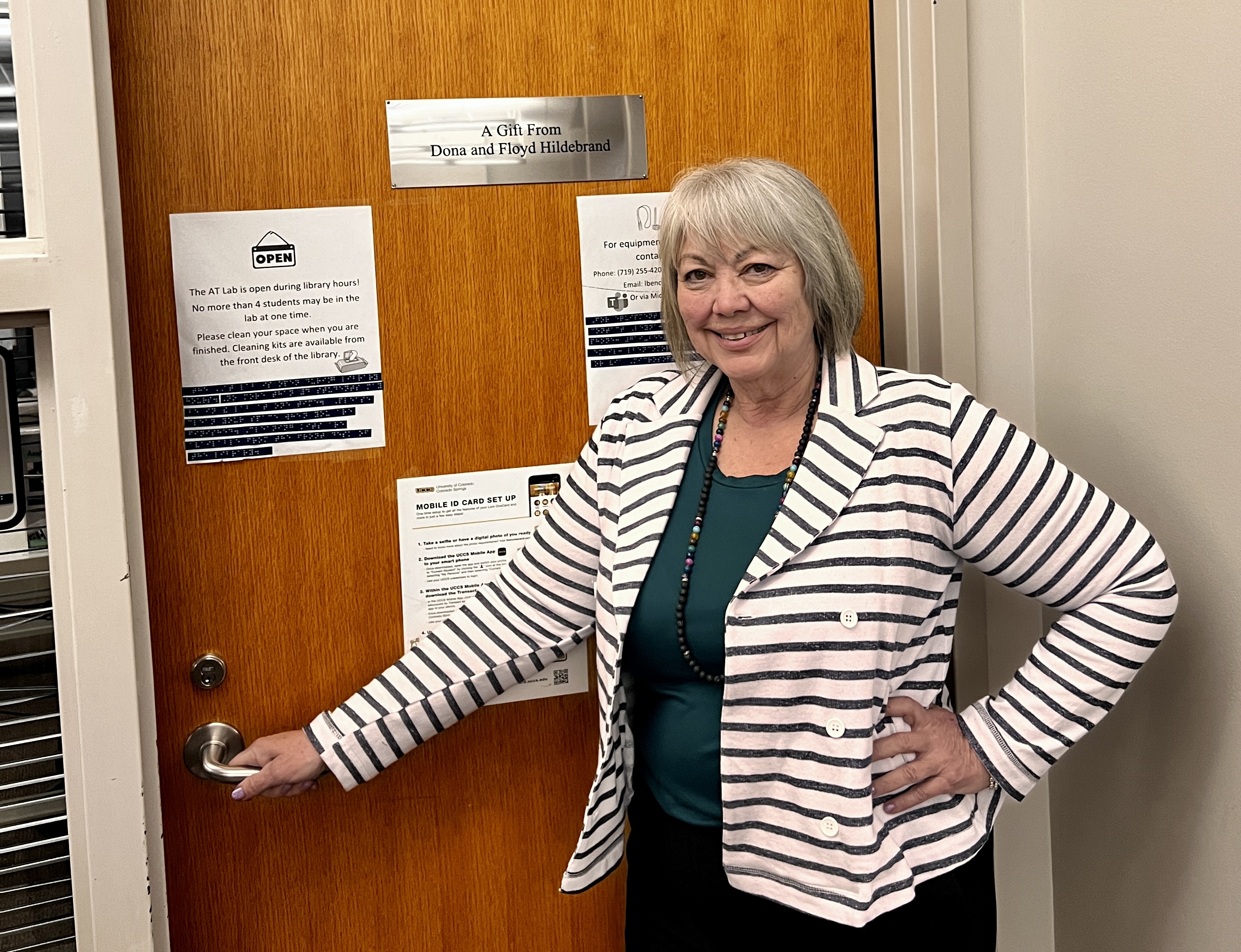 Assistive Technology Specialist Leyna Bencomo standing in front of the door to the Assistive Technology Lab