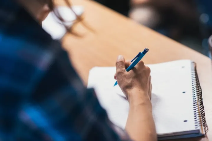 Student taking notes in a notebook during class